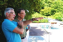 Das Foto zeigt zwei Männer in einem Schwimmbad. Ein Mann erklärt dem anderen etwas.