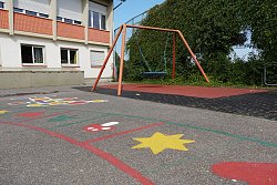 Pausenhof Hort Luisenschule, Blick über den asphaltierten Hof mit bunten Kindermalereien hinüber zur großen Korbschaukel