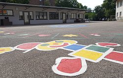 Blick über den Pausenhof Hort Luisenschule mit bunten Kindermalereien auf dem Asphalt, im Hintergrund Gebäude