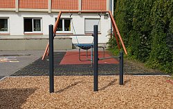 Stufenreck auf dem Pausenhof beim Hort Luisenschule, als Fallschutz dienen Holzschnitzel, im Hintergrund die Korbschaukel und ein Drehgerät sowie das Gebäude des Horts, rechts sind Büsche