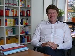 Mats Tilebein, Justiziar der Stadt Lahr und Leiter des Rechts- und Ordnungsamts in seinem Büro. Hinter ihm steht ein großes volles Bücherregal.