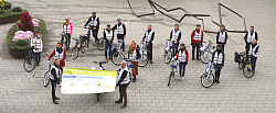 Alle Teilnehmenden der Verantstaltung stehen auf dem Rathausplatz in voller Fahrradmontour und mit Fahrrad. Das Foto wurde aus Vogelperspektive aufgenommen. 