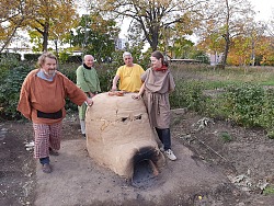 Experimentalarchäologe Frank Wiesenberg räumt behutsam die ungebrannten, zerbrechlichen Tonarbeiten in den Lahrer Töpferofen. Aufmerksam beobachten ihn die Perlendreherin Alaka Harkort und Prof. Dr. Helmut Köser, der Initiator des Alamannendorfes Vörstetten