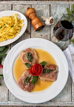 Ein Teller mit drei Stück Fleisch in Soße, ein weiterer Teller mit Nudeln