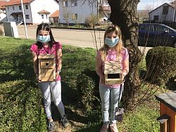 Das Bild zeigt zwei Mädchen, die ihre selbstgebastelten Nistkästen präsentieren