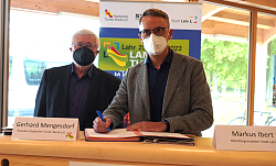 Landesturnfest 2022 - Vertragsunterzeichnung Gerhard Mengesdorf, Präsident Badischer-Turner-Bund, und OB Markus Ibert stehen an einem Turnkosten. Ob Ibert unterzeichnet den Vertrag. 