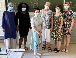 Ärztin Thi Dai Trang Nguyen (Mitte) mit Dozentin und Kursteilnehmerinnen atehen zum Gruppenbild mit Maske vor einer Schultafel. 