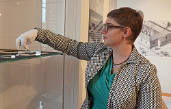 Kuratorin Kathrin Lieb legt mit weißen Händen ein Ausstellungsstück in die Vitrine