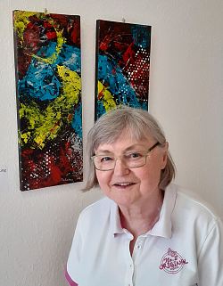 Monika Endres vor einem ihrer Monoprinten in den Farben blau, gelb und rot