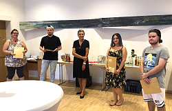 Die Absolventen stehen im Halbkreis. Jeder hat sein Zeugnis in der Hand. 