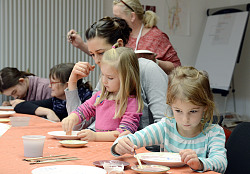 Das Bild zeigt Kinder und Erwachsene beim Teller bemalen