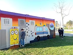 Drei Jugendliche stehen vor einer großen Containerwand, die mit Graffiti bunt besprüht wurde.