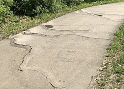 Radweg am Fachmarktzentrum mit Wurzeleinwüchsen. Man sieht wie die Wurzeln den Belag anheben und zum Reißen gebracht haben.