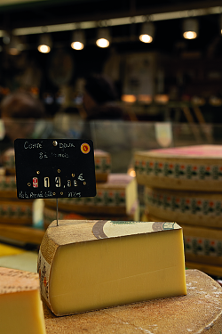 Ein Stück Käse auf einem Käselaib.