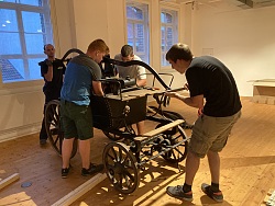 Vier Personen beim Aufbau eines alten Holzlöschwagens 