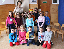 Oberbürgermeister Ibert sitzt in einer Schar von Kindern, die das Bilderbuch hoch halten.