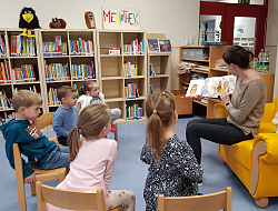 Eine Mutter sitzt im Stuhlkreis mit mehreren Kindern und zeigt ein Bilderbuch.