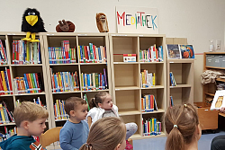 Eine Mutter sitzt im Stuhlkreis mit mehreren Kindern und zeigt ein Bilderbuch.