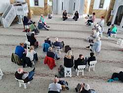 Mehrere Menschen sitzen beisammen, um einer Vorlesung zu lauschen.