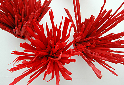 Ein Kunstwerk von Reinhard Sigle, bei dem rote Holzstücke gebündelt an der Wand hängen.