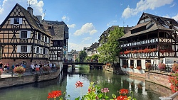 Durch Straßburg fließt ein Fluss, an dessen Seiten sich Häuser und Blumen reihen.