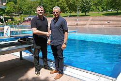 Bob Jones übernimmt die Leitung der Lahrer Bäderbetriebe von Claude Woitschitzky (von links). Beide stehen vor dem Springerbecken des Terrassenbades Lahr und geben sich die Hand.