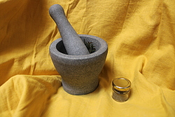 In einem Mörser aus Stein werden Salz und Kräuter zu Kräutersalz gemahlen. 