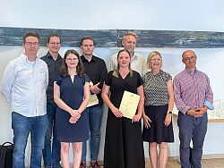 Die Absolventen stehen umringt von ihren Lehrern mit den Zeugnissen in der Hand. 