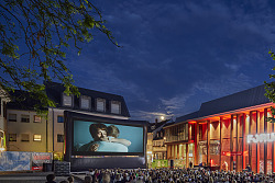 Eine große Menge an Menschen von hinten  auf dem Lahrer Urteilplatz, welche gespannt auf die große Leinwand schauen und den Film genießen 