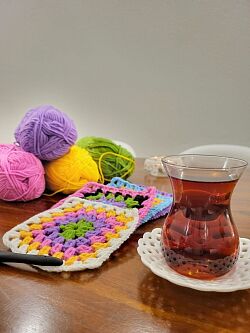 Bunte Wolle, Strickwaren und ein Glas Tee