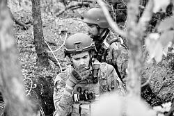Das Schwarzweiß-Foto zeigt einen Soldaten im Wald, der eine Zigarette raucht.