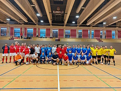 Fußballteams in roten, blauen, weißen und gelben Trikots in einer Halle