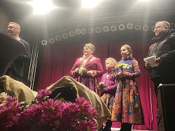 Auf der Chrysantrhemenbühne stehen der Oberbürgermeister Ibert, die Chrysanthemenkönigin Marion die zweite und ihre zwei Blumenmädchen sowie ein dunkel gekleiderter Mann 