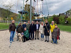 Gruppe von elf Personen auf einer Sandfläche vor einer Bewegungsanlage