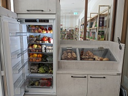 Das Foto zeigt den geöffneten Kühlschrank in der Mediathek Lahr, voll bepackt mit Lebensmitteln, daneben die reichlich gefüllte Brotschublade