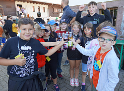 Kinder stehen im Halbkreis und stoßen mit Getränkeflaschen in der Mitte an. 