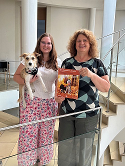Zwei Frauen mit Hund und Programmheft im Treppenhaus der Volkshochschule Lahr