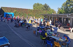 Im Hof vom Hort sind Verkaufstische aufgebaut. Man sieht das bunte Treiben um die Tische herum.