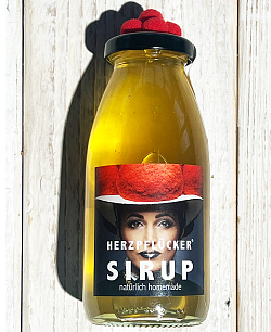 Großaufnahme einer Flasche Herzpflücker-Sirup, auf dem Deckel befindet sich ein roter Bollenhut