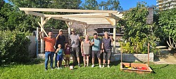 Mitarbeiter der Firma Freischlad und Ehrenamtliche des Interkulturellen Gartens stehen vor der gemeinsam fertiggestellten Pergola im Interkulturellen Garten Lahr, realisiert 2024 über den Lahrer Stadtgulden