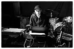 Auf dem Bild sieht man Konrad Sprenger inmitten von Mischpult und Schlagzeug