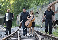 Das Foto zeigt die „Grenzgänger“ mit ihren Instrumenten, sie laufen auf einem Bahngleis
