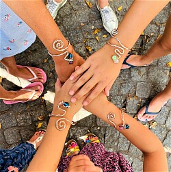 Das Foto zeigt 4 Kinderhände mit Armreife aus ineinander verschlungenen Drähten.&#13;&#10;