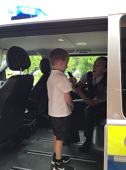Das Foto zeigt einen kleinen Jungen mit einer Polizistin im offenen Polizeikombi. Er darf in das Funkgerät sprechen.