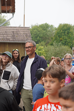 Oberbürgermeister Markus Ibert besucht die Kinder und Betreuer der Stadtranderholung auf dem Langenhard. Er ist steht in Mitten einer Traube aus Kindern.