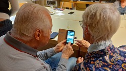 Zwei Senioren tauschen sich bei der Bedienung eines Handys aus