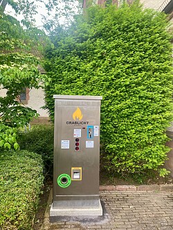 Grablichtautomat vor einer Hecke