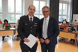 Mann in Feuerwehruniform erhält Urkunde von Mann im Anzug