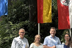 Gruppenbild von links Markus Ibert, Oberbürgermeister Stadt Lahr; Katharina Tränkle, Amt für Gewerbeaufsicht und Immissionsschutz; Nikolas Stoermer, Erster Landesbeamter; Teresa Frenssen, Projektleiterin E-Werk Mittelbaden; Bernhard Palm, Vorstandsvorsitzender E-Werk Mittelbaden vor wehenden Fahnen beim Landratsamt Offenburg. &#13;&#10;&#13;&#10;