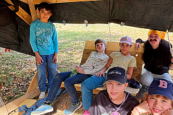 Kinder sitzen in einer selbstgebauten Hütte auf dem Freizeithof Langenhard. 